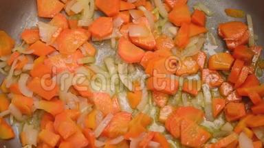 炒菜的过程-胡萝卜和洋葱与油在金属锅。 特写视图